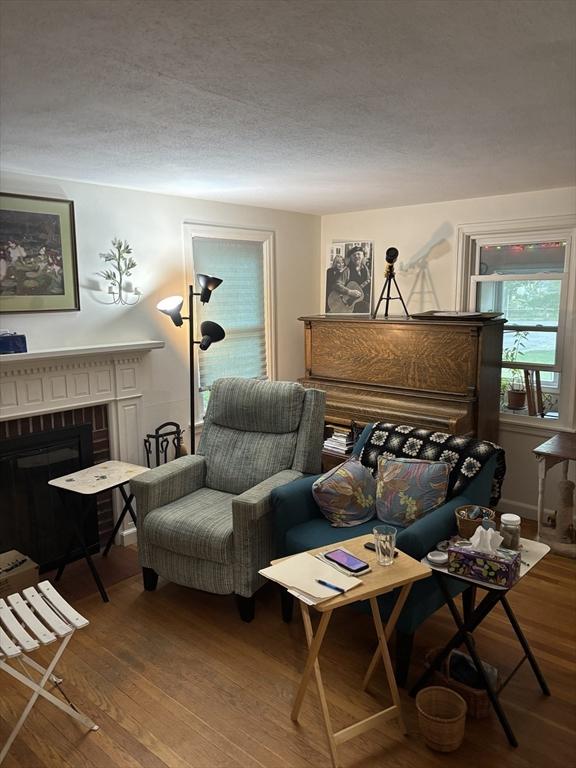 14 Anderson Ave, Holyoke, MA 01040 - living area featuring wood finished floors, a brick fireplace, and a textured ceiling