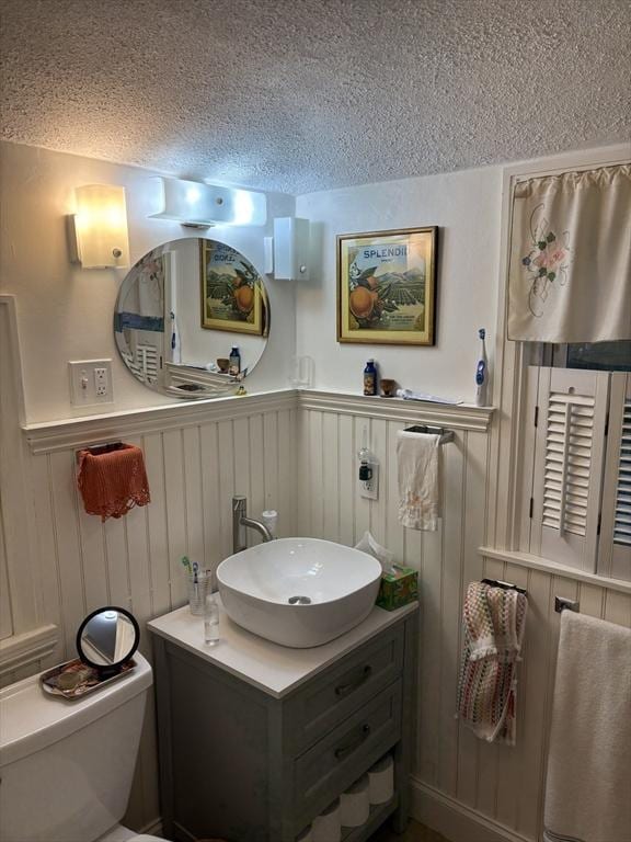 14 Anderson Ave, Holyoke, MA 01040 - half bath featuring a textured ceiling, toilet, vanity, and wainscoting
