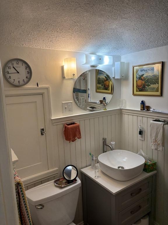 14 Anderson Ave, Holyoke, MA 01040 - half bath featuring a textured ceiling, a wainscoted wall, toilet, and vanity
