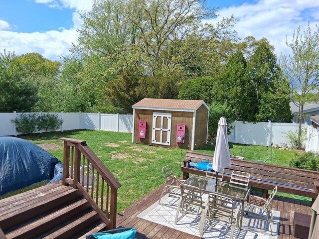 view of yard featuring outdoor dining area, a shed, a deck, and an outdoor structure