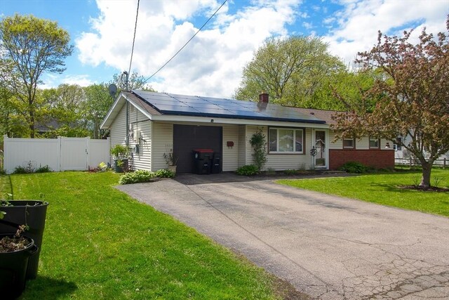 single story home featuring an attached garage, driveway, and roof mounted solar panels