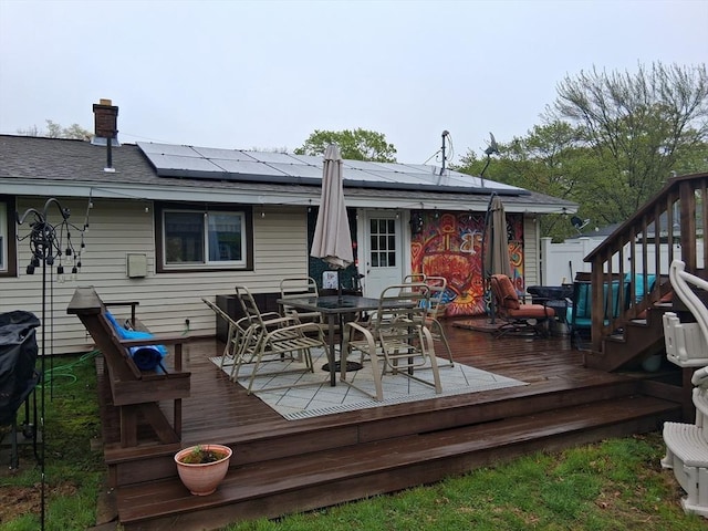 rear view of property with outdoor dining area, solar panels, and a deck