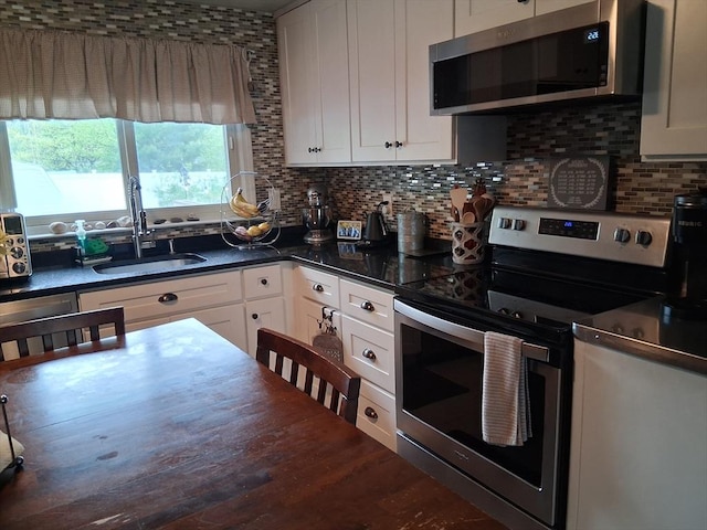 kitchen featuring stainless steel appliances, a sink, dark countertops, tasteful backsplash, and white cabinets