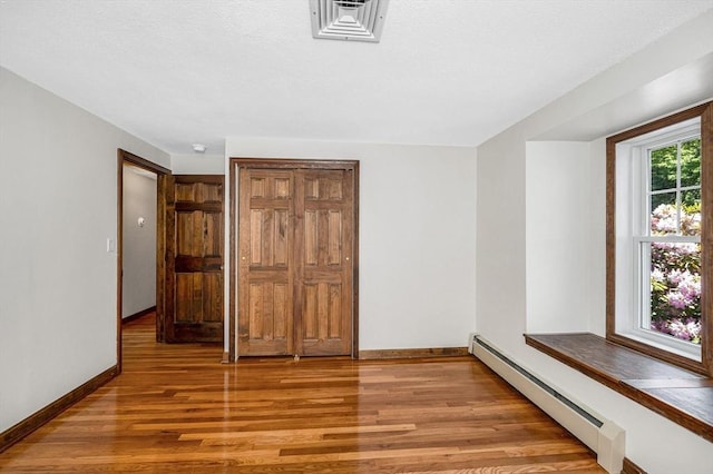 18 Patriot Rd, Tewksbury, MA 01876 - unfurnished bedroom featuring light wood finished floors, baseboard heating, baseboards, and a closet