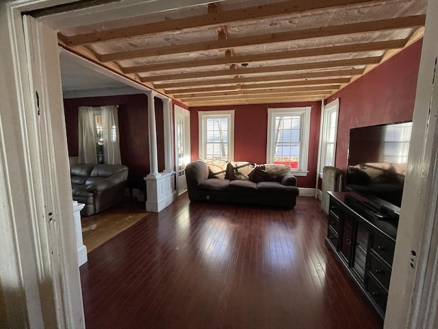 living room featuring ornate columns, dark wood finished floors, and beamed ceiling