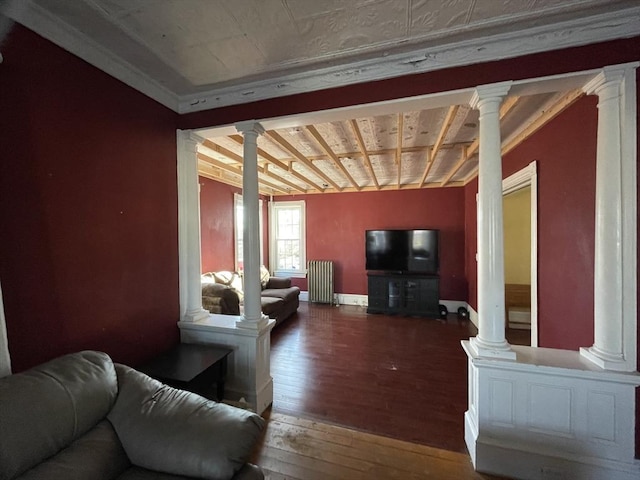 living area featuring decorative columns, baseboards, radiator heating unit, and hardwood / wood-style floors