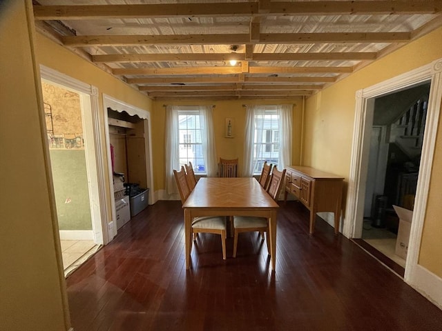 dining space with dark wood-type flooring, beam ceiling, and baseboards