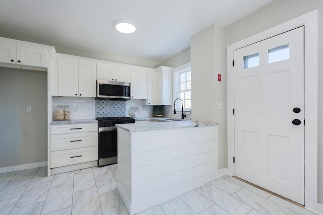 kitchen with tasteful backsplash, white cabinetry, sink, and appliances with stainless steel finishes