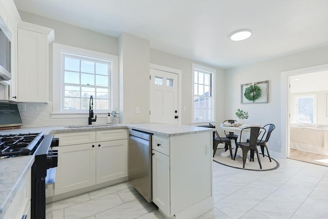 kitchen with sink, light stone countertops, tasteful backsplash, white cabinetry, and stainless steel appliances