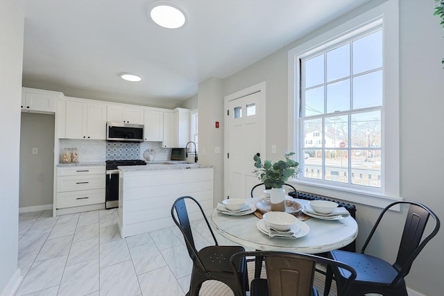 kitchen featuring sink, light stone counters, backsplash, white cabinets, and appliances with stainless steel finishes