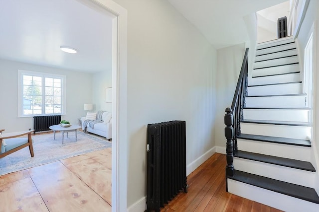 stairway featuring hardwood / wood-style floors and radiator heating unit