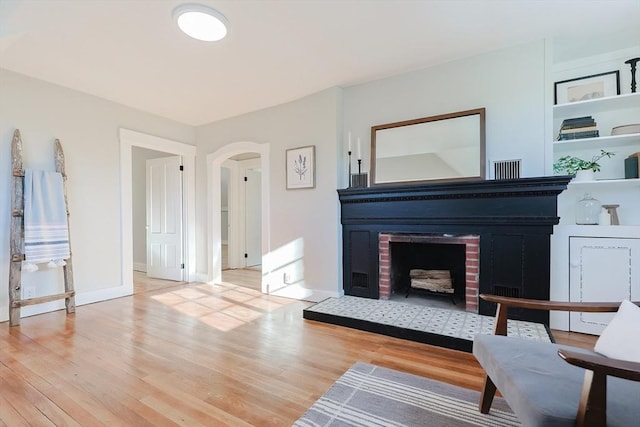 living area featuring a brick fireplace and light wood-type flooring