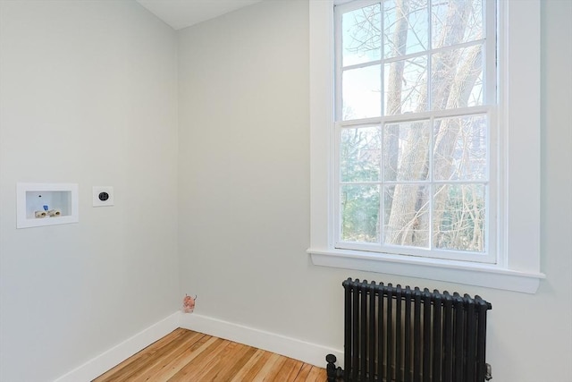 washroom with radiator heating unit, plenty of natural light, washer hookup, and hardwood / wood-style floors