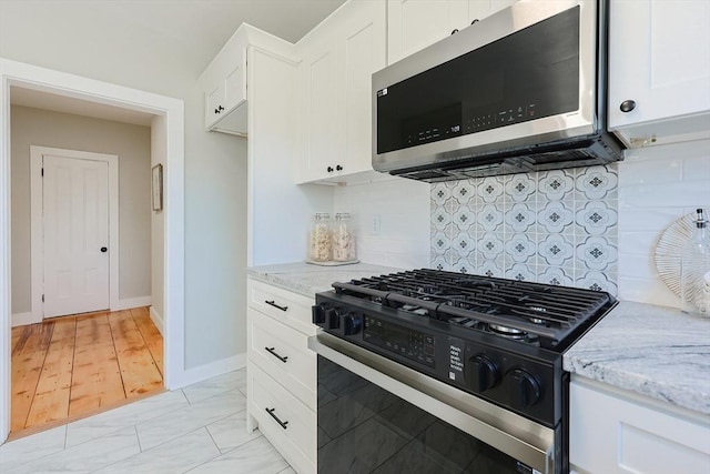 kitchen featuring backsplash, light stone counters, white cabinets, and stainless steel appliances