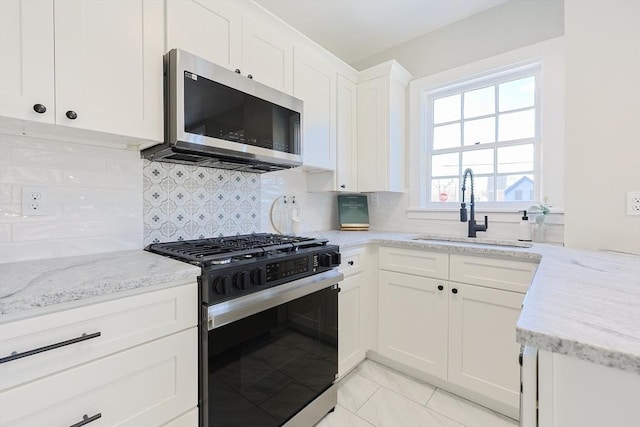 kitchen with backsplash, sink, white cabinetry, and stainless steel appliances