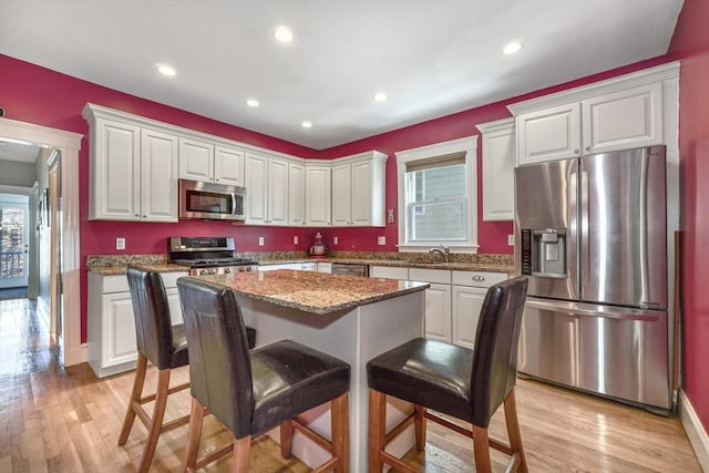 kitchen featuring white cabinetry, light hardwood / wood-style flooring, stainless steel appliances, and a kitchen island