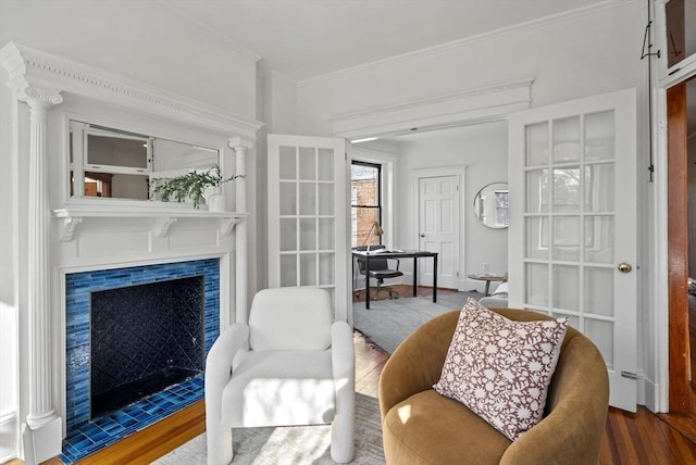 living area featuring crown molding, a fireplace with flush hearth, and wood finished floors