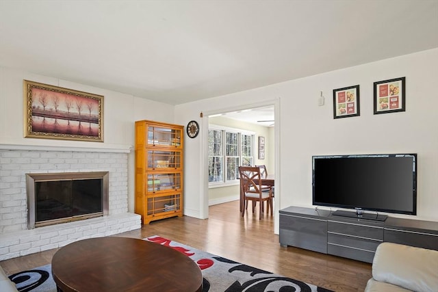 living room with wood finished floors and a brick fireplace