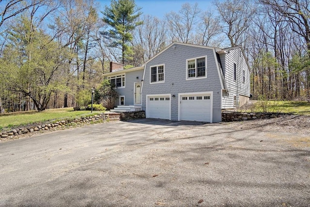 view of home's exterior featuring driveway, a garage, and a chimney
