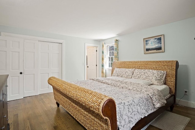 bedroom with a closet, dark wood-type flooring, and baseboards