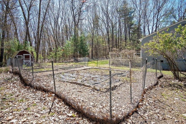 view of yard featuring a garden, a storage shed, an outbuilding, and fence
