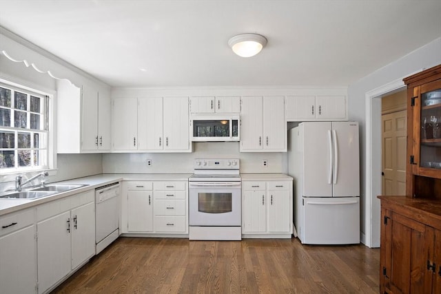 kitchen with white appliances, light countertops, a sink, and dark wood-type flooring