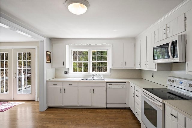 kitchen featuring white appliances, a sink, light countertops, and white cabinetry
