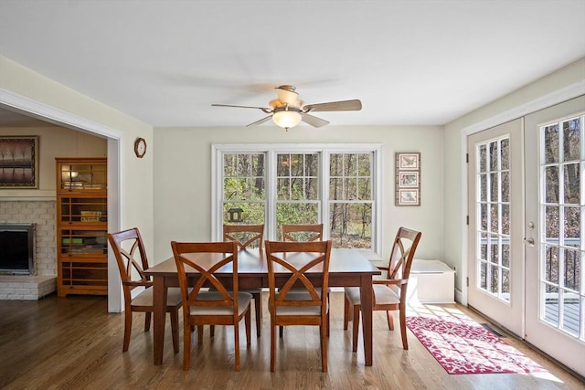 dining space featuring french doors, wood finished floors, ceiling fan, and a fireplace