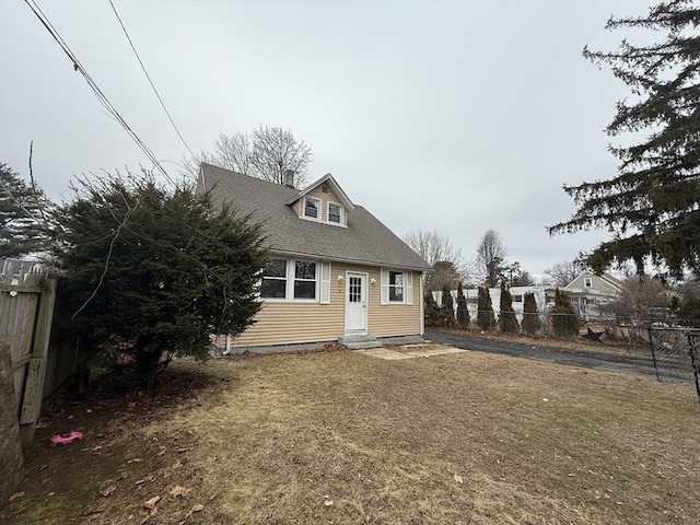 view of front of property with entry steps, a shingled roof, and fence