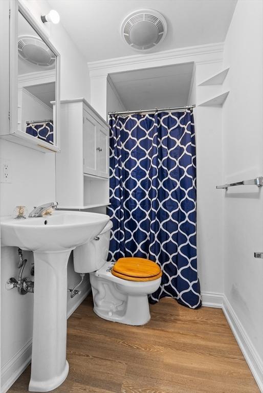 bathroom featuring hardwood / wood-style flooring, toilet, and crown molding