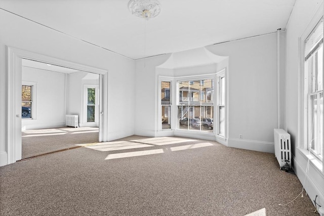 carpeted empty room featuring radiator heating unit