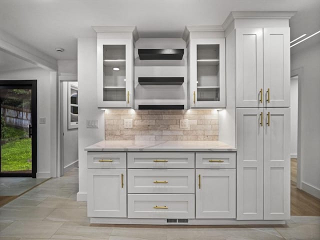 820 N King St, Northampton, MA 01060 - kitchen featuring decorative backsplash, glass insert cabinets, light stone counters, and white cabinets