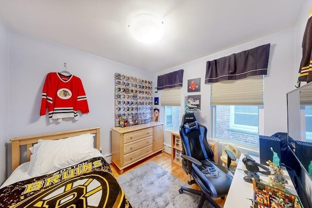 bedroom featuring light wood finished floors and a baseboard heating unit