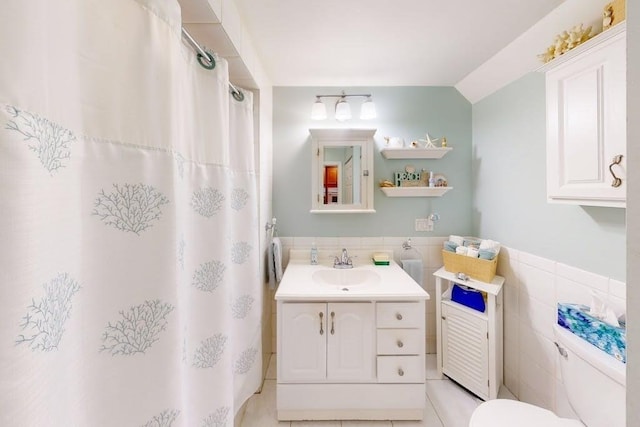 bathroom with tile walls, toilet, tile patterned floors, vanity, and vaulted ceiling