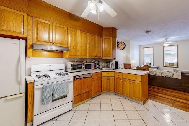 kitchen with white appliances, under cabinet range hood, a ceiling fan, a peninsula, and light countertops