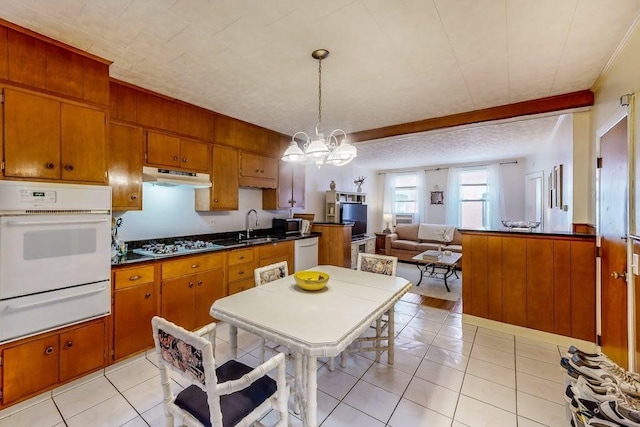 kitchen featuring white appliances, a warming drawer, under cabinet range hood, and brown cabinetry