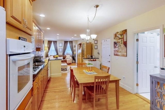 dining room featuring a chandelier, light wood-type flooring, baseboards, and recessed lighting