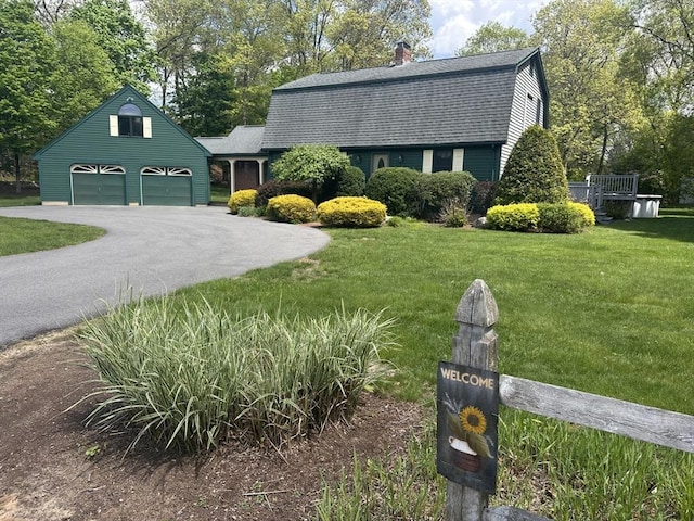 colonial inspired home with a gambrel roof, roof with shingles, a garage, and a front yard