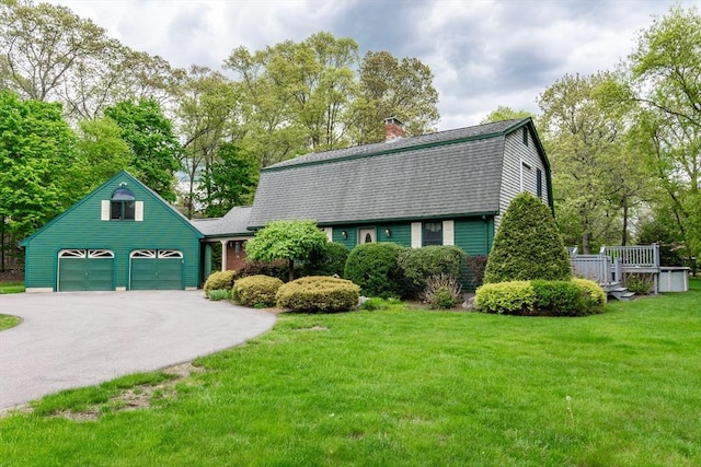 dutch colonial with a gambrel roof, a garage, driveway, a front lawn, and roof with shingles