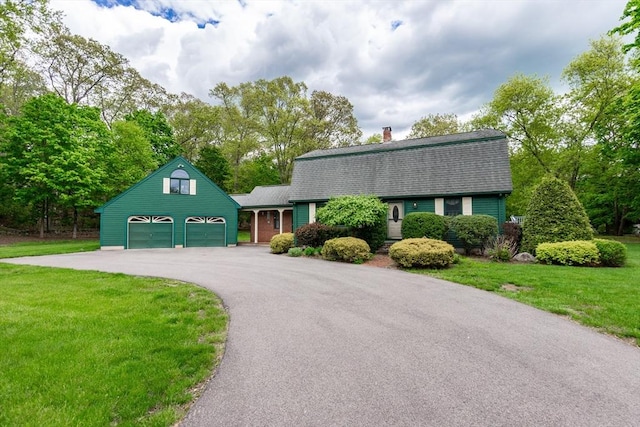 colonial inspired home featuring a gambrel roof, roof with shingles, asphalt driveway, and a front lawn