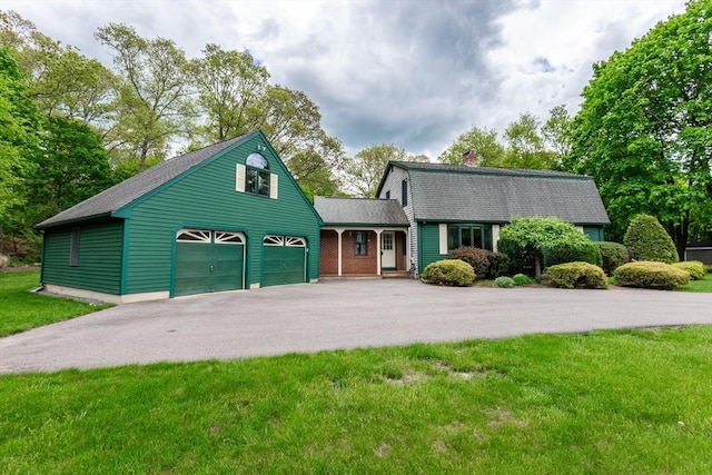 dutch colonial with asphalt driveway, a shingled roof, a front yard, a chimney, and a gambrel roof