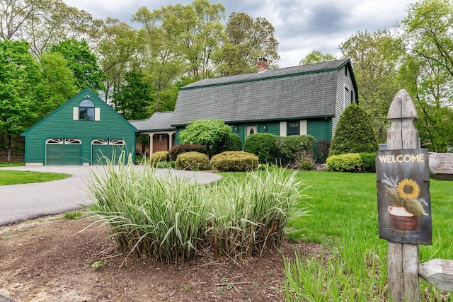 dutch colonial featuring a gambrel roof, roof with shingles, a chimney, and driveway