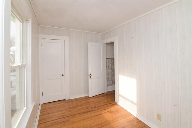 spare room with ornamental molding and light wood-type flooring