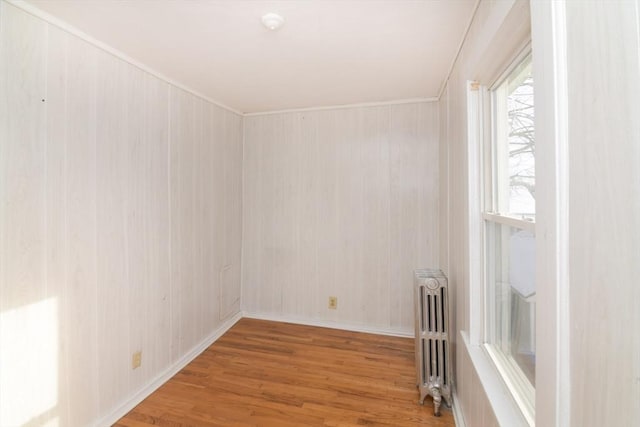 empty room with ornamental molding, radiator, and hardwood / wood-style floors