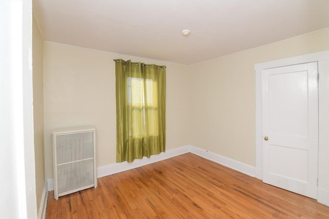 unfurnished room featuring hardwood / wood-style flooring and radiator heating unit