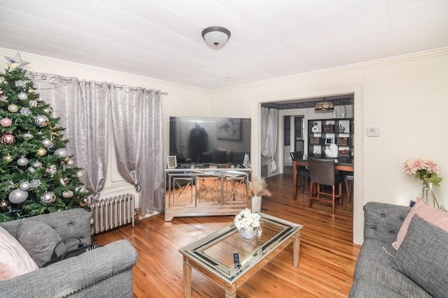 living room featuring hardwood / wood-style floors, radiator heating unit, and ornamental molding