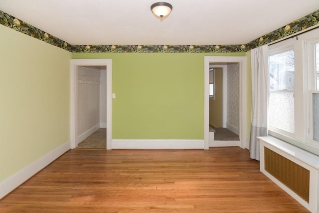 spare room featuring radiator and light hardwood / wood-style floors