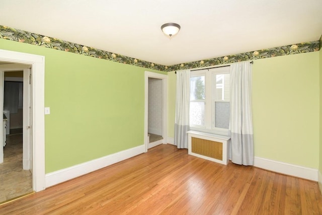 empty room featuring radiator heating unit and light wood-type flooring