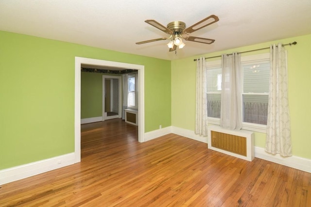 spare room with ceiling fan, radiator heating unit, and light wood-type flooring