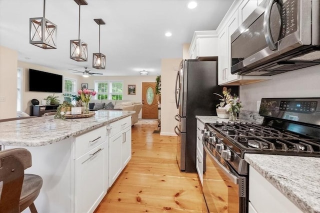 1085 Southbridge Rd, Warren, MA 01585 - kitchen with appliances with stainless steel finishes, open floor plan, light wood-type flooring, a kitchen bar, and white cabinetry